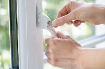 Close Up Of Woman Turning Key In Window Lock